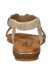 Gouden metalen sandalen hebben een gevoerde bruine binnenzool, een gestructureerd oppervlak en elastische banden met geschulpte randen.