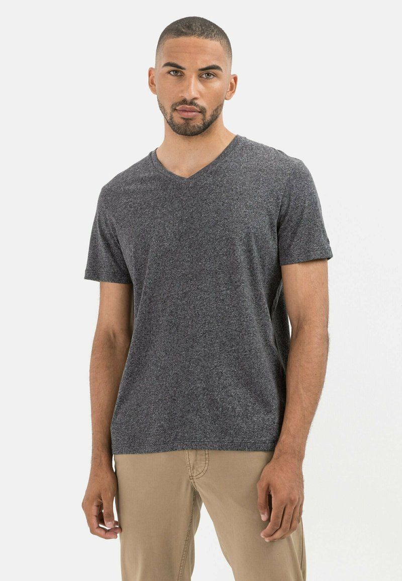 Donkergrijs v-hals t-shirt gemaakt van zachte, gestructureerde stof met korte mouwen, gecombineerd met lichtbeige broeken, staand tegen een witte achtergrond.