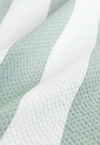 Texturierten Stoff mit alternierenden mintgrünen und weißen Streifen, wobei ein gestepptes Muster visuelle Tiefe und weiche Rillen erzeugt.