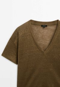Haut marron à manches courtes en mélange de lin avec texture visible et petite étiquette de marque noire à l'intérieur de l'encolure en V.