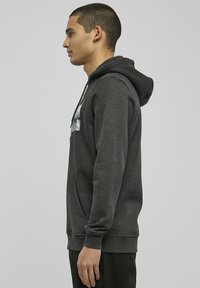 Grå hettegenser laget av myk stoff, med kengurulomme, snøring i hetten og trykk foran. Slim fit med ribbestrikket kant og mansjetter.