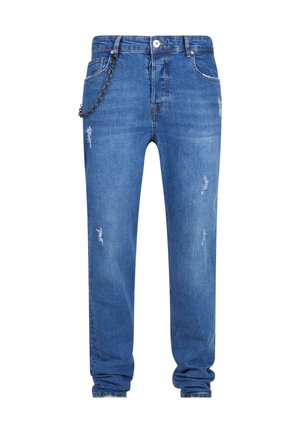 Zili džinsi ar brīvu piegriezumu, kuriem ir nolietotas detaļas, ķēdes akcenti uz kreisā jostas cilpas un taperēti iekakli pie potītēm.