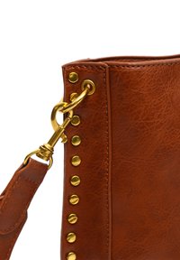 Borsa in finta pelle marrone con hardware dorato, inclusi un gancio e borchie lungo il lato. Superficie testurizzata e dettagli della tracolla robusti.
