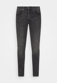 Slim-fit svarta urtvättade jeans med knapp framtill, bältesöglor och fem fickor, visade mot en vit bakgrund.