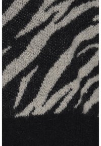 Svart och krämfärgad stickad tyg med zebrarandigt mönster. Mjuk textur med en blandning av fibrer, som visar kontrasterande färgsektioner.