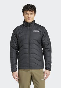 Black insulated jacket with a zip front, featuring a quilted design and high collar. The logo "TERREX" is visible on the left chest.
