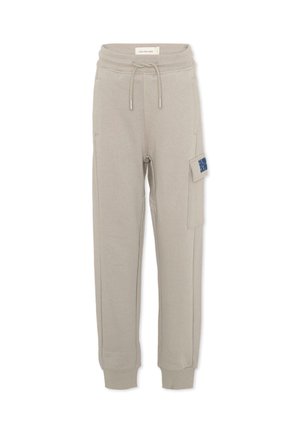 Beżowe bawełniane spodnie dresowe z elastycznym pasem, sznurkiem do regulacji, ściągaczami przy kostkach oraz prawą kieszenią typu cargo z niebieskim napisem.