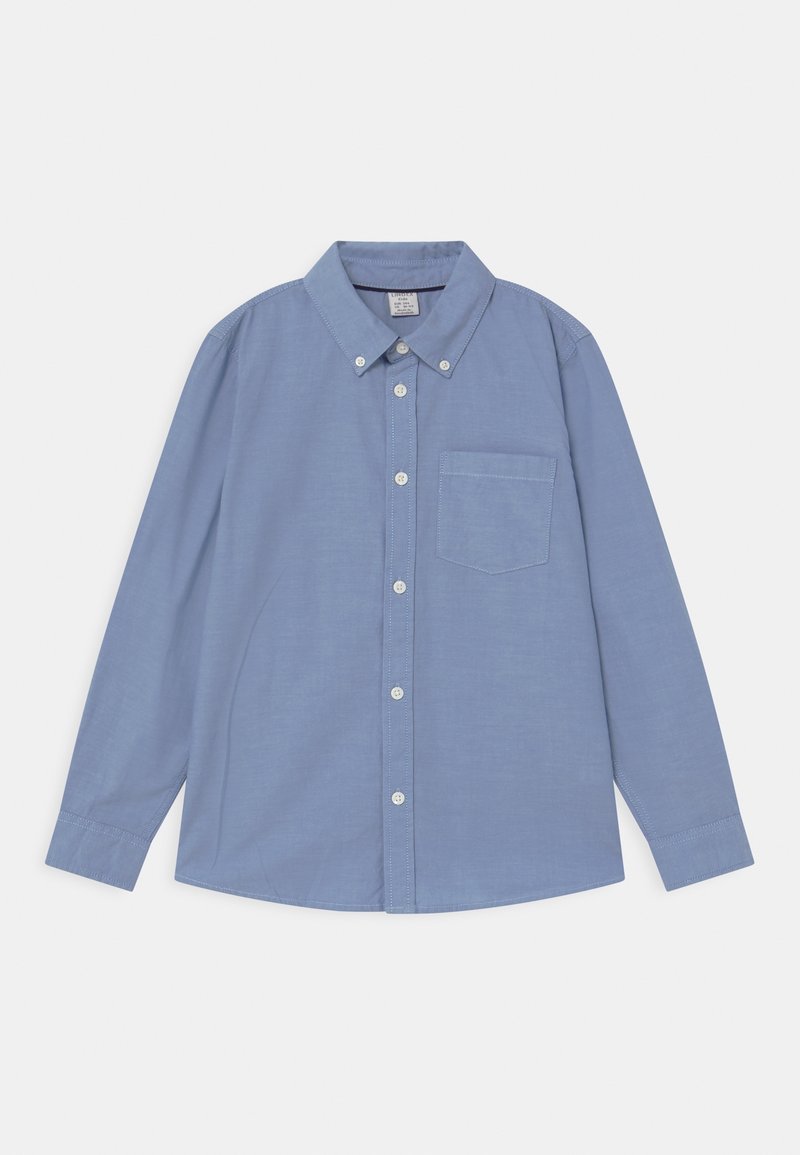 Chemise bleu clair à manches longues avec boutons, col et une poche poitrine, posée à plat sur un fond blanc.