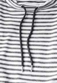 Hoodie med svart och vitt horisontellt randigt mönster, med svarta snören med silverändar, texturerad tyg.