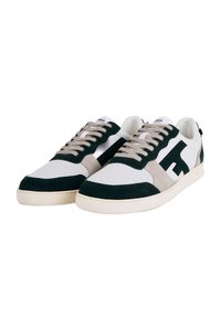 Baskets blanches et vert foncé avec des accents beiges, présentant une tige perforée, du daim texturé, des lacets classiques et un détail de logo sur le côté.