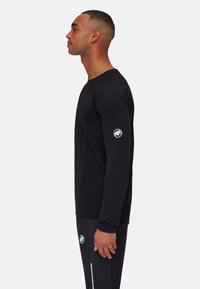 Zwart sportshirt met lange mouwen en een aansluitend ontwerp, gemaakt van gladde stof. Heeft een rond logo op de linker mouw.