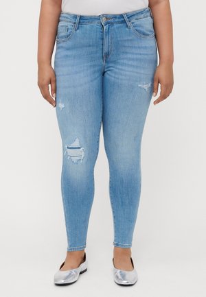 Light blue skinny jeans with distressed detailing on the thighs, five-pocket design, and a button-front closure. Worn with silver flats.