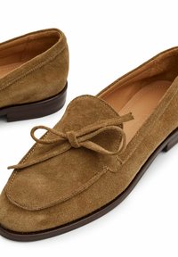 Hnědé semišové loafers s kulatou špičkou, detaily krajkového uzlu a nízkým dřevěným podpatkem. Měkká textura s jemnými švy.