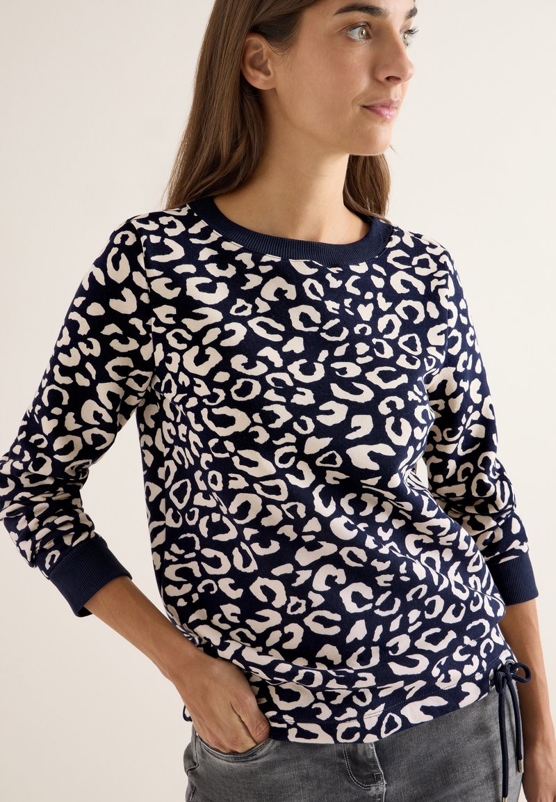 Sudadera de punto en color azul marino con estampado de leopardo blanco. Cuenta con un cuello redondo, mangas largas con puños acanalados y un dobladillo ajustable con cordón.