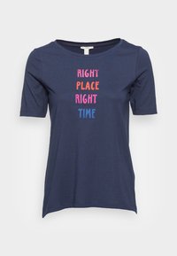 Camiseta de manga corta azul marino hecha de algodón suave, con texto colorido: "EN EL LUGAR Y EN EL MOMENTO ADECUADOS" en rosa, naranja y azul.
