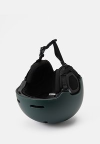 Musta ja tummanvihreä kypärä, joka on sileän pyöreä muotoiltu, sisävuorattu pehmustuksella, säädettävillä hihnoilla ja ilmanvaihtoventtiileillä.