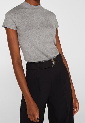 Graues kurzärmeliges Strickoberteil mit hohem Kragen, kombiniert mit schwarzen Hosen und einem breiten Gürtel mit einer runden Schnalle. Texturiertes und tailliertes Design.