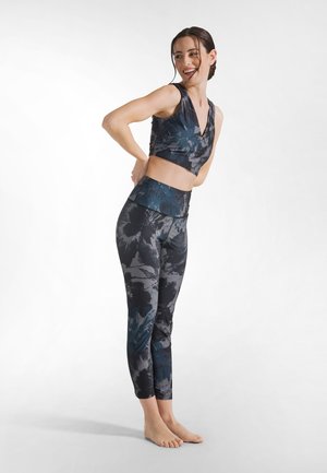 Sæt med sports-bh og leggings med et mørkt blomsterprint i nuancer af blå og grå, lavet af elastisk materiale med en tætsiddende pasform.
