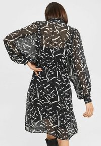 Schwarzes, transparentes Kleid mit abstraktem weißen geometrischen Muster, Ballonärmeln, taillierter Taille und lässiger Passform.