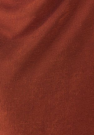 Raundika värviga sooniline kangas, millel on pehmed voldid ja peened püstised jooned, luues tekstuuriga pinnaprofiile.