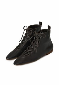 Stivali alla caviglia in pelle nera con punta affusolata, lacci anteriori con asole, linguette posteriori e suole piatte marroni.