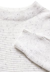 Pull en laine blanc avec une texture côtelée, présentant des éclats noirs. Gros plan sur le col et les détails des poignets.