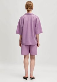 Paarse oversized shirt en bijpassende shorts van zachte katoen, met een ontspannen fit en verlaagde schouders, met platte naden en zonder zichtbare patronen.