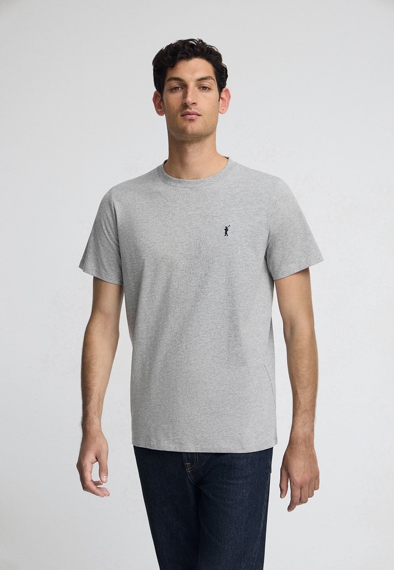 Grijze katoenen t-shirt met korte mouwen, ronde hals en een klein zwart logo op de linkerborst. Soepele textuur en casual pasvorm.