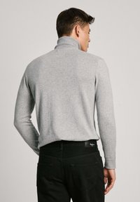 Grijze coltrui met lange mouwen, geribbelde kraag en mouwen, gecombineerd met zwarte broek met een logo-tag op de tailleband.