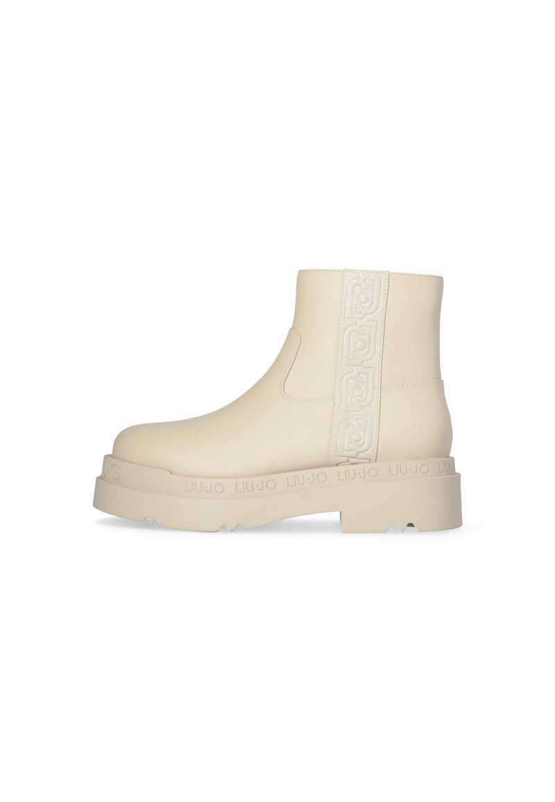 Stivaletti beige alla caviglia con un esterno in gomma liscia, caratterizzati da un logo imbottito decorativo sul lato, suola spessa e punta rotonda.