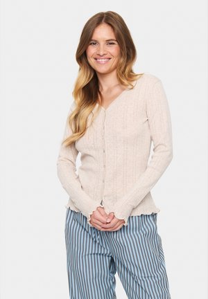 Light pink cardigan made of textured knit fabric with vertical stripes, featuring a V-neck, front buttons, and scalloped hemline.