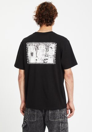 Schwarzes Baumwoll-T-Shirt mit einem großen weißen Grafikdruck auf dem Rücken, der abstrakte Gesichter und Figuren darstellt. Kurze Ärmel, lockere Passform.