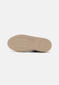 Semelle de chaussure en caoutchouc beige avec des motifs de grip texturés et une finition lisse. Dispose d'une bande de roulement en forme de losange pour la traction et la durabilité.