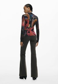 Pikkade varrukatega pluus erksate värvide ja tekstuuridega värvikireva graafilise mustriga. Sobitatud lehvivate oliiviroheliste pükstega, millele lisanduvad mustad jalatsid.