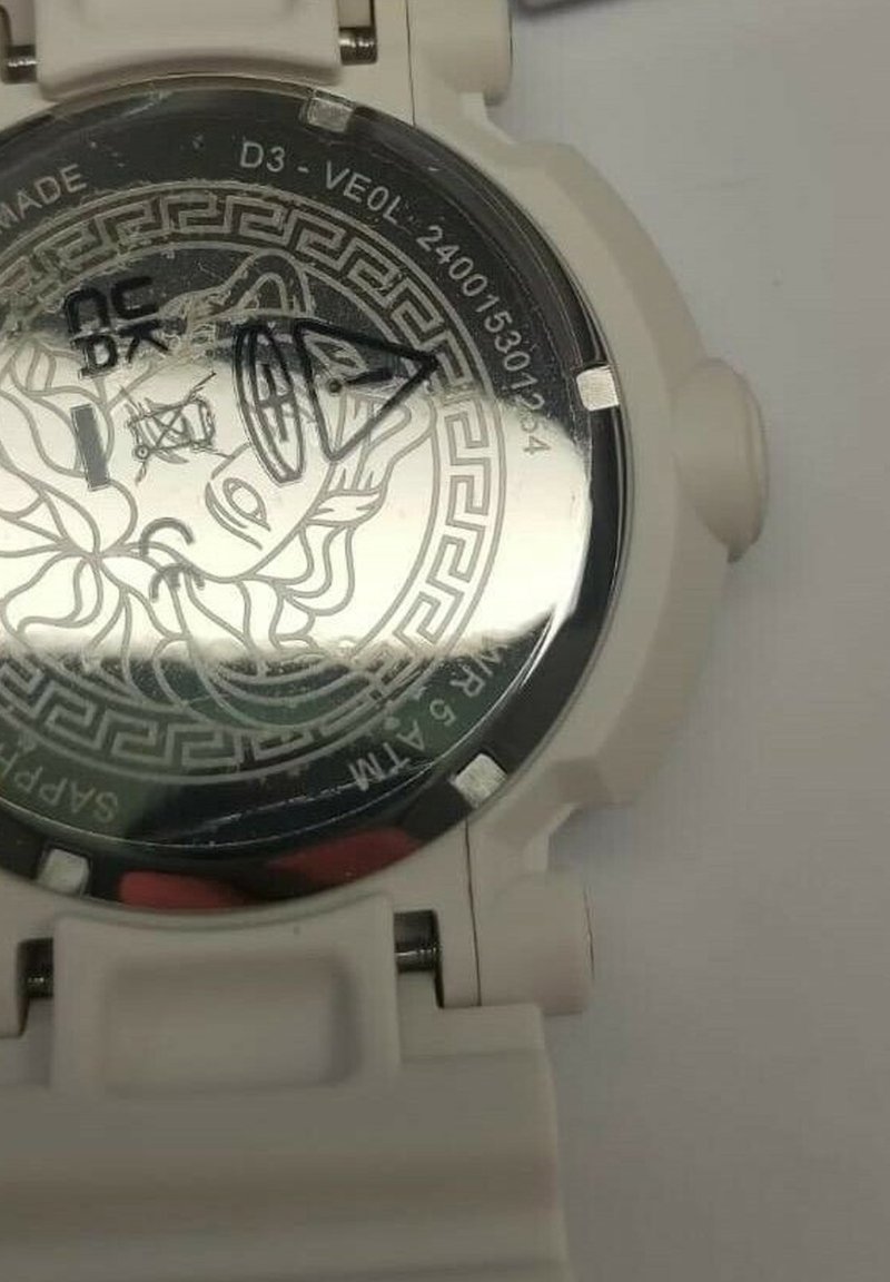 Witte horloge met een gebloemd zilveren achterdeksel, waarop een leeuwenkop is afgebeeld. Kenmerken zijn een duurzame band en een indicatie van waterbestendigheid.
