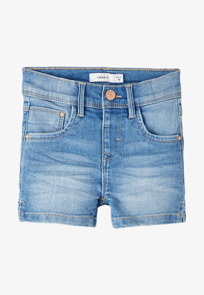 Short en denim bleu clair pour tout-petit avec poches avant, boutons en cuivre, passants de ceinture et une étiquette de taille à l’intérieur de la ceinture.