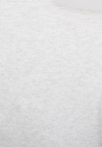 Ljusgrå stickad tröja med ett ribbat mönster och rund halsringning. Har ett mjukt tyg och subtila färgvariationer.