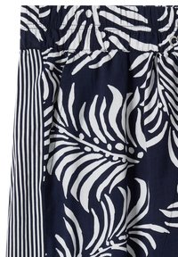 Navy blue fabric with white tropical leaf print and vertical white stripes, elastic waistband visible at the top.