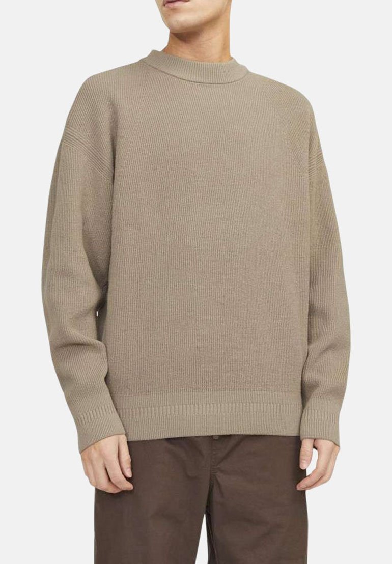 Pull en maille côtelée beige avec un col montant, coupe décontractée et ourlet côtelé. La texture semble douce et légèrement extensible.