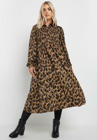 Sukienka maxi w panterkę w kolorze brązowym i czarnym, z falbanistą górą, długimi rękawami i zwiewnym fasonem. Zestawiona z czarnymi botkami za kostkę.