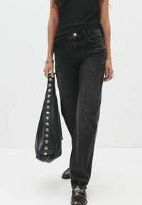Jeans z leopardjim vzorom v čiernej farbe s vysokým pásom, skombinované s čiernou koženou taškou so striebornými gombíkmi. Oblečenie dopĺňajú tmavé topánky.