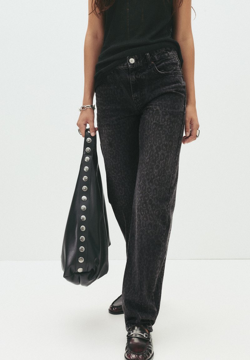 Jeans z leopardjim vzorom v čiernej farbe s vysokým pásom, skombinované s čiernou koženou taškou so striebornými gombíkmi. Oblečenie dopĺňajú tmavé topánky.