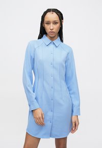 Lichtblauwe jurk met lange mouwen, een knoopsluiting aan de voorkant, een klassieke kraag en een slanke pasvorm, met verticale naden en een gladde textuur.