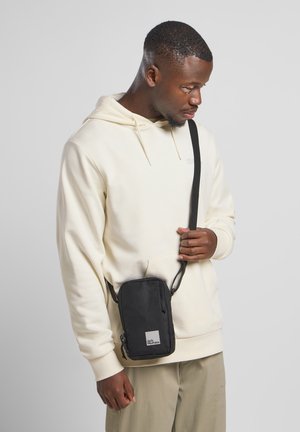 Borsa a tracolla nera realizzata in tessuto resistente, forma rettangolare, con tasca frontale con zip e logo del marchio sul fondo.