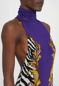 Lila ärmelloses Kleid mit hohem Kragen, versehen mit einem Zebramuster und floralen Akzenten in Gelb und Pink. Glatter, dehnbarer Stoff.