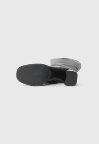 Bottine en cuir noir à bout carré, surface lisse, petit talon carré et design simple. Semelle extérieure en caoutchouc noir pour une meilleure adhérence.