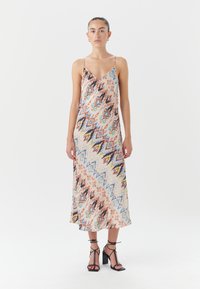Satin midi suknelė su V formos iškirpte ir plonomis petnešėlėmis, turinti spalvingą abstrakčią modelį oranžinės, mėlynos ir geltonos spalvų. Juodos blokinės pirštinės sandalai.