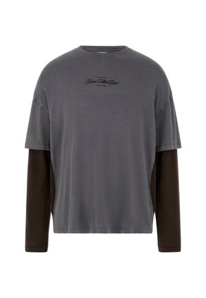 Grå kortærmet t-shirt med lange brune ærmer, lavet af blødt stof. Har et diskret logo i sort på brystet og detaljer på sidepanelet.