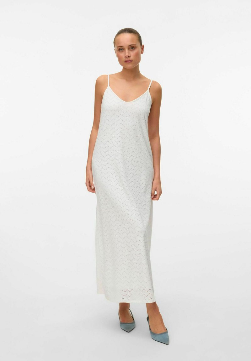 Witte maxi-jurk met een V-hals en dunne bandjes, met een zigzagpatroon en een gladde textuur, gecombineerd met puntige blauwe hakken.