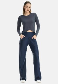 Navy athletic pants with a wide waistband and two front pockets, paired with a gray long-sleeve top featuring a cropped design.
